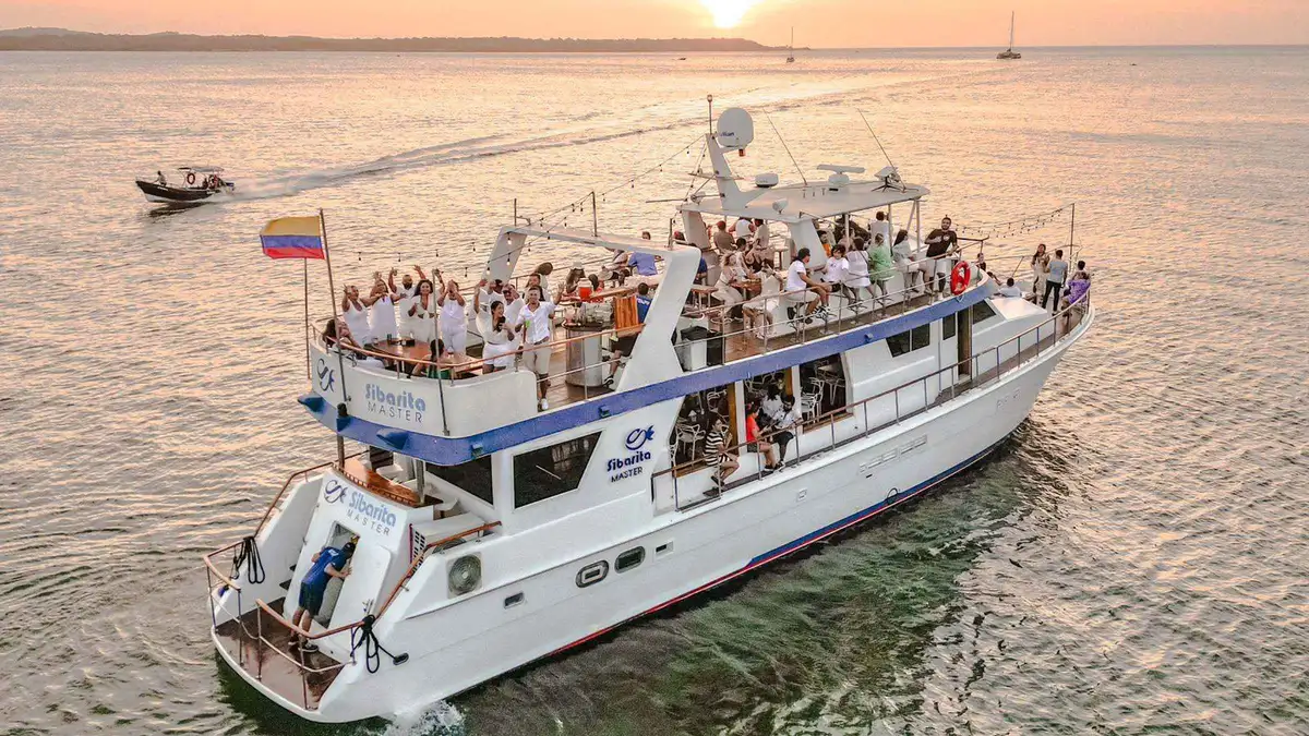 Guests toasting drinks aboard an open-bar yacht at sunset in Cartagena Bay, Colombia
