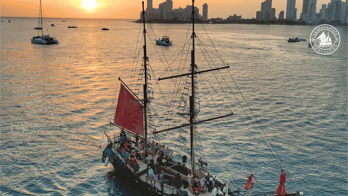 A themed pirate ship sailing Cartagena Bay at sunset with passengers on deck, Colombia