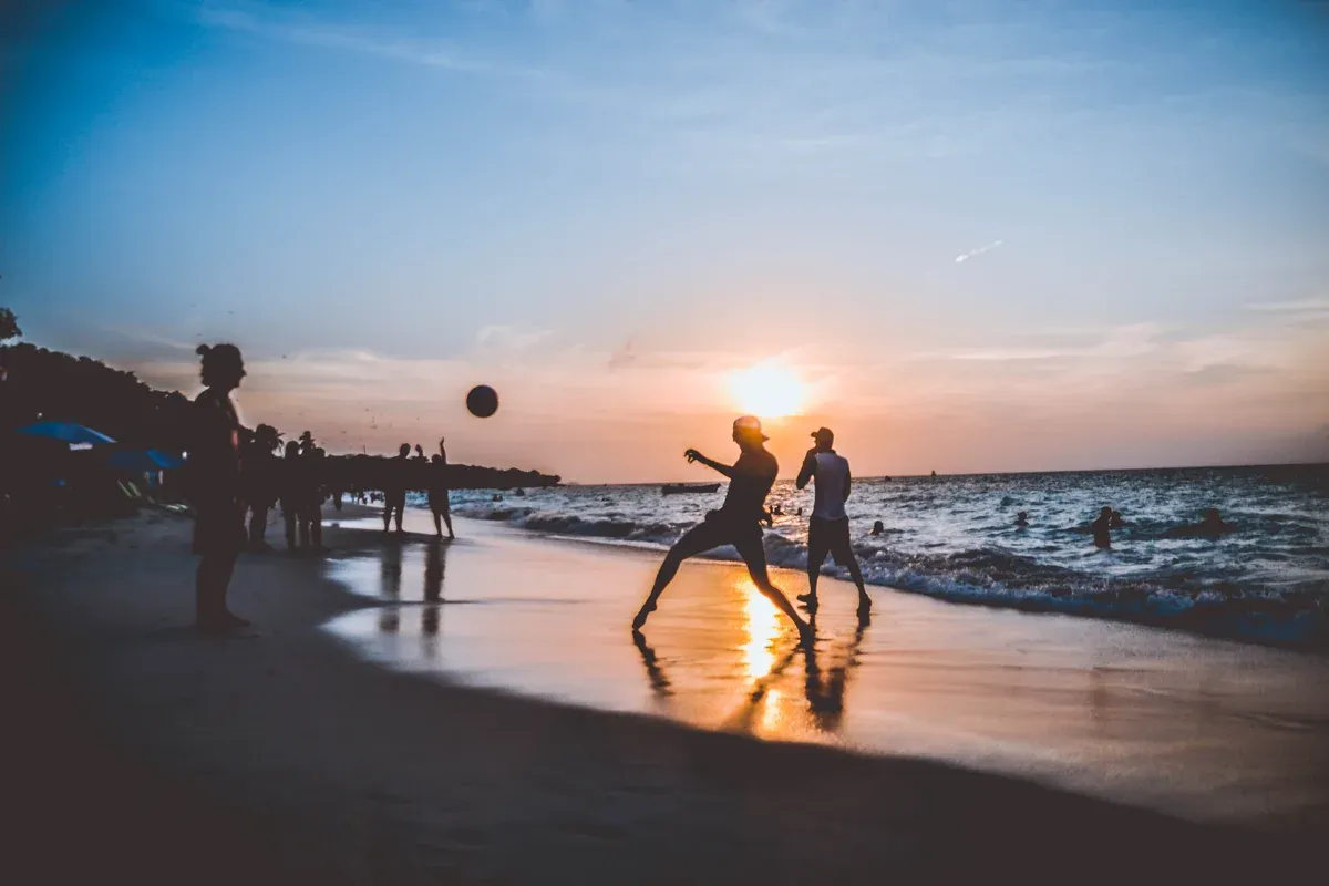Beach football game in silhouette at sunset on Playa Blanca, a day trip from Cartagena, Colombia